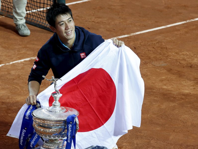 Kei Nishikori con su trofeo y la bandera de su país 