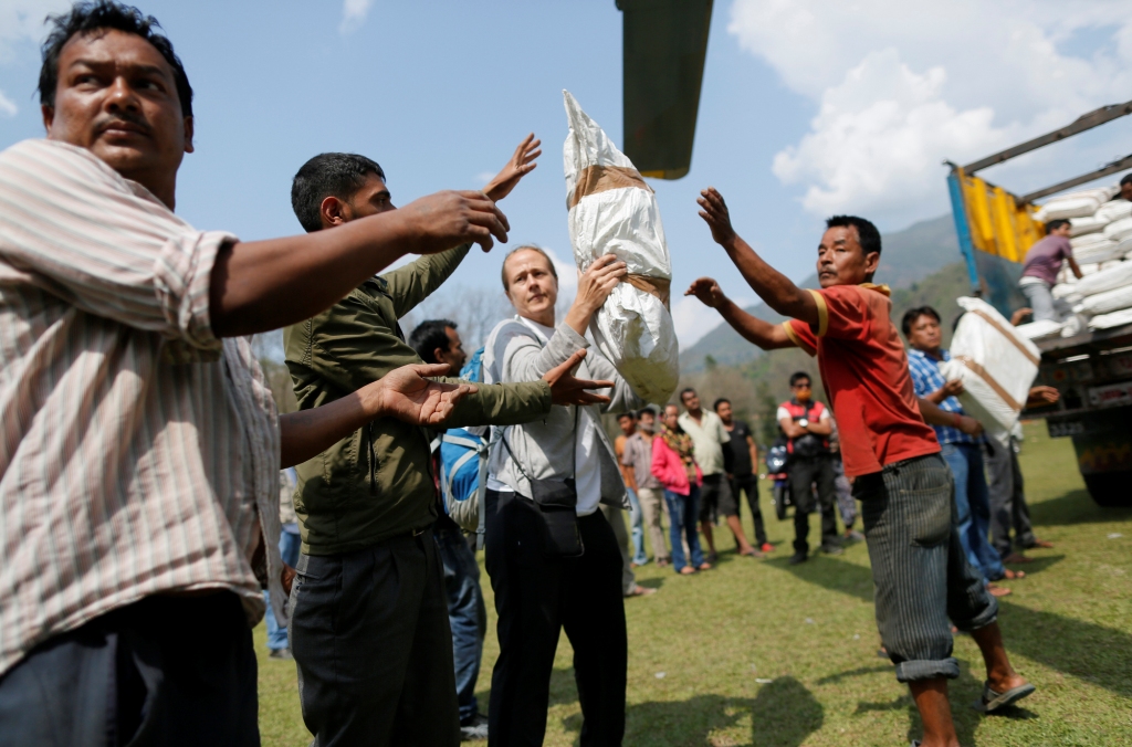Voluntarios bajan cargamento de arroz y azúcar de un helicótero cerca de donde fue el epicentro del terremoto