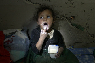 Un niño yemení come un yogurt en un túnel para el agua hecho por el hombre donde su familia busca refugio tras perder su casa en Saná