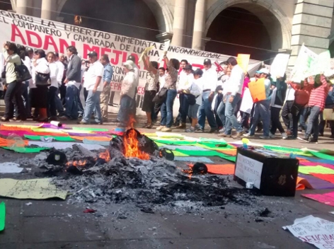Trabajadores sindicalizados del gobierno de Oaxaca inconformes con el aumento salarial que lograron quemaron ataúdes, gorras  y uniformes, frente al  
