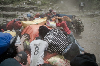 Habitantes de Barpak, en el norte de Nepal, se protegen del polvo levantado por un helicóptero indio al despegar, junto a la comida proporcionada