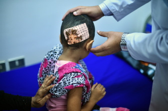 Un doctor examina una herida de bala en la cabeza de una niña, refugiada yemenita en Yibuti, causada por un francotirador en Adén