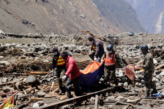 Residentes de Langtang ayudan al personal de rescate a trasladar un cadáver, hallado entre los restos de la aldea de Langtang