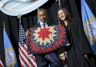 Barack Obama sostiene una colcha que le han regalado después de hablar en una ceremonia en un instituto de Watertown, en Dakota del Sur