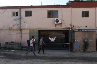 Dos afganos caminan junto a puerta del Park Palace, la casa de huéspedes de Kabul que sufrió un ataque terrorista