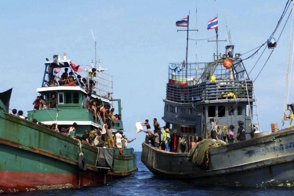 Pescadores dan provisiones a inmigrantes en un bote a la deriva.