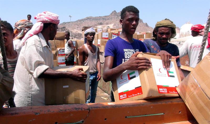Trabajadores yemeníes descargan un cargamento de ayuda de los Emiratos Árabes Unidos, en un barco en el puerto sureño de Adén