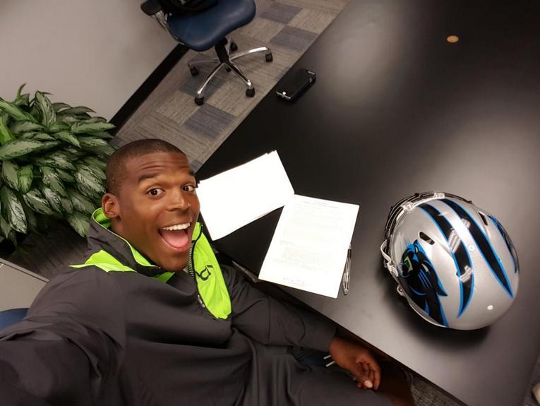 Cam Newton firmando su extensión de contrato