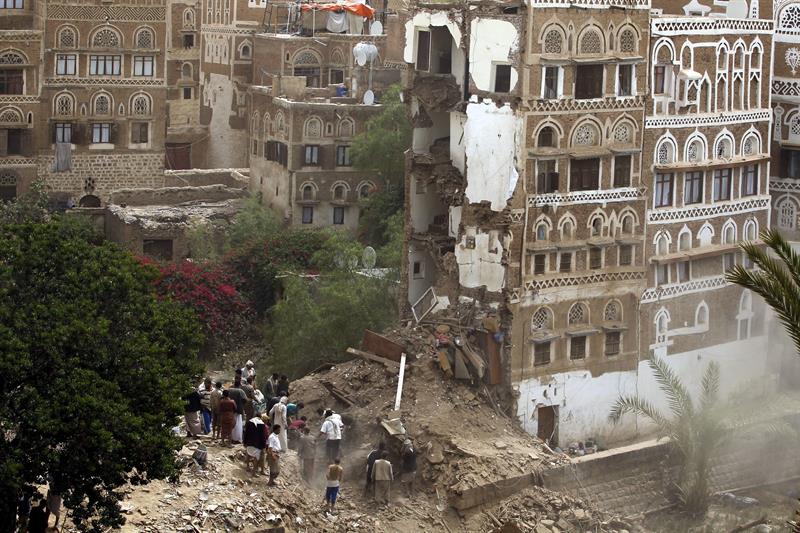 Varias personas buscan supervivientes entre los restos de varios edificios destrozados tras el bombardeo en el casco histórico de Saná