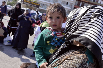 Una mujer sostiene a su hijo, mientras ella y otros emigrantes esperan para ser trasladados en el puerto de Mitilene, en la isla griega de Lesbos