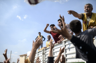 Refugiados sirios se aprovisionan de ayuda humanitaria junto al puesto fronterizo turco de Akcakale, provincia de Sanliurfa