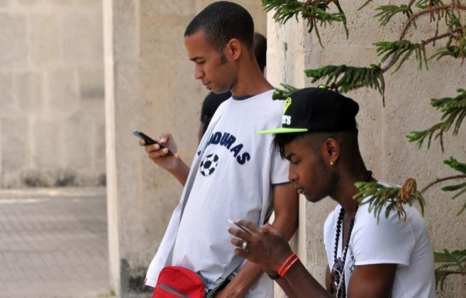Dos jóvenes cubanos consultan sus teléfonos celulares en La Habana