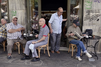 Varios ciudadanos griegos leen la prensa o conversan en un café del centro de Atenas