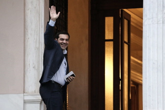 El primer ministro griego, Alexis Tsipras, saluda a los periodistas al llegar a un encuentro con miembros de su gobierno en Atenas