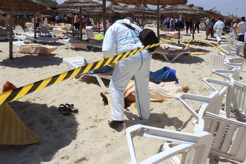 Un policía examina a dos víctimas del ataque terrorista de hoy en uno de los hoteles de Susa, en Túnez 
