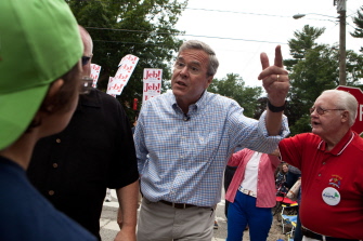 Jeb Bush responde a una activista del cambio climático que le hace varias preguntas en el desfile del 4 de julio en Amherst, New Hampshire