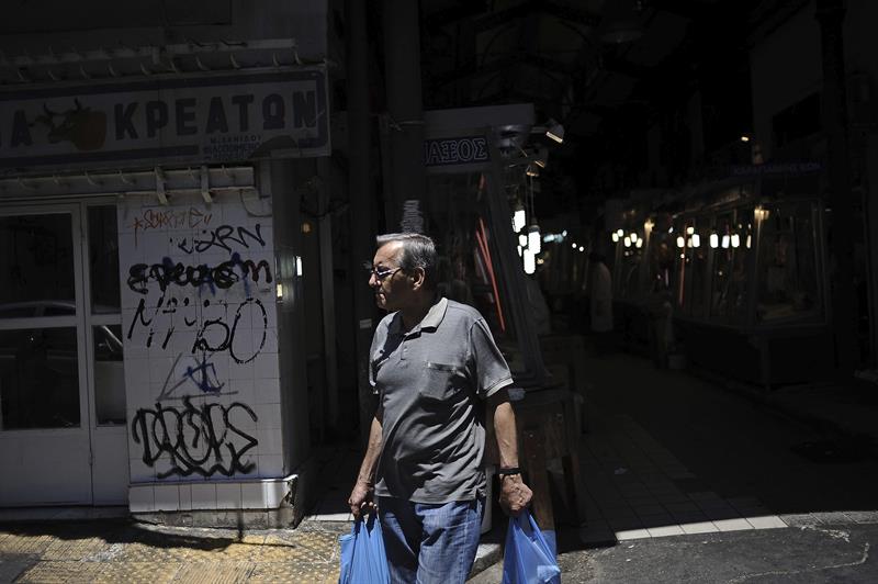 Un hombre abandona un mercado en Atenas tras haber realizado hoy sus compras