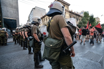 Policías griegos hacen guardia ante activistas que protestan contra una manifestación proeuropea en el centro de Atenas