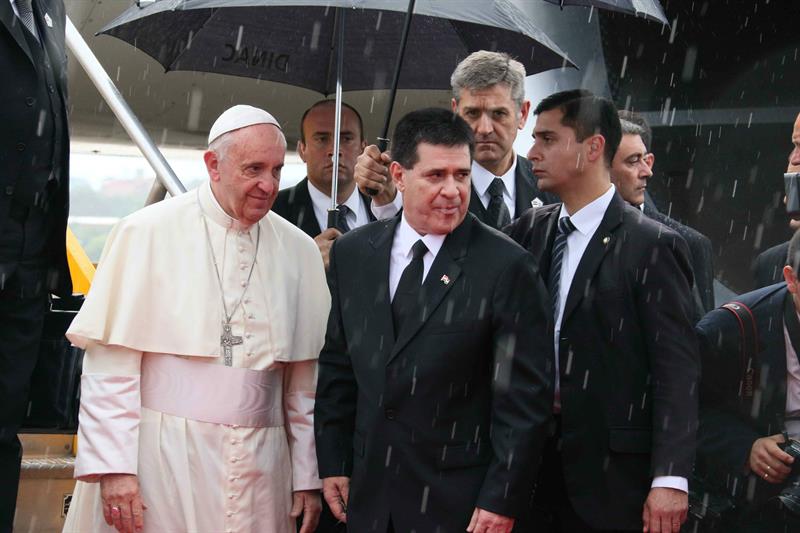 El papa Francisco (i) es recibido por el presidente paraguayo, Horacio Cartes (c), en el aeropuerto Silvio Pettirossi de Asunción
