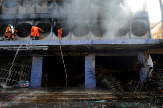 Bomberos intentan apagar el fuego de unos edificios tras una explosión causada por militantes separatistas en Sungai Kolok, Narathiwat