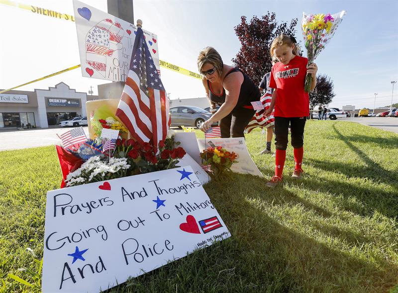 Una familia deja flores en un memorial instalado cerca del edificio de reclutamiento militar de EU hoy tras el tiroteo en Chattanooga 