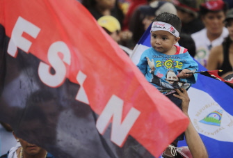 Un niño, junto a una bandera del Frente Sandinista de Liberación Nacional en la celebración del 36 aniversario de la revolución, en Managua 