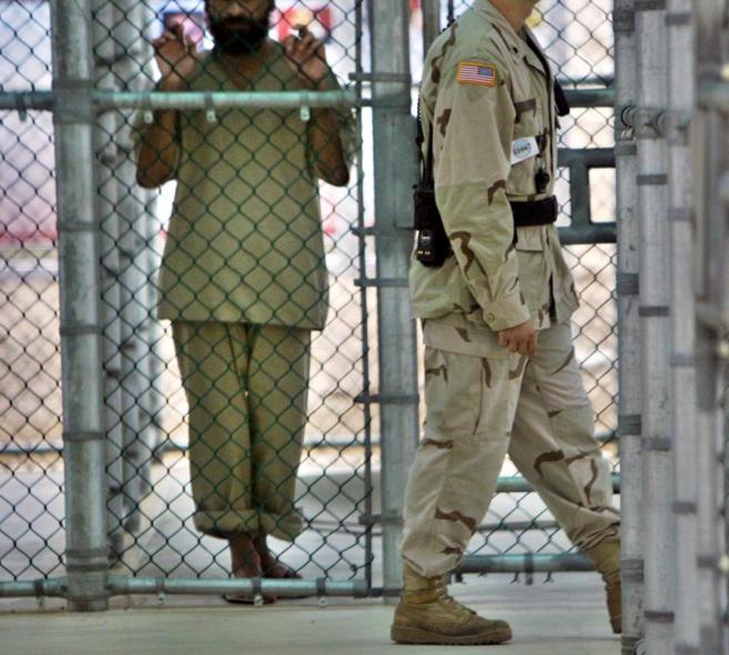Un soldado estadunidense camina junto a uno de los detenidos en la base de Guantánamo