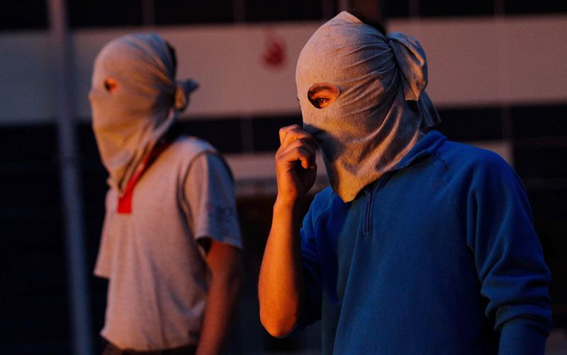 Manifestantes con máscaras esperan ante una barricada ardiendo durante los choques de hoy con la policía turca en el distrito Gazi de Estambul