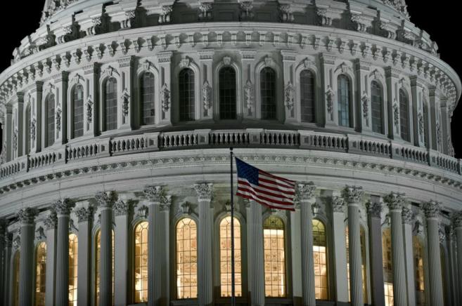 Imagen nocturna del Capitolio en Washington, con la bandera de Estados Unidos ondeando