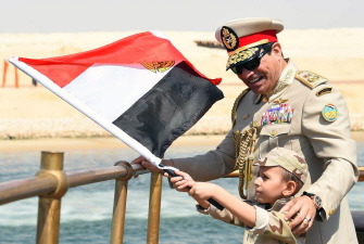El presidente egipcio Abdel Fatah al-Sisi sonríe mientras un niño ondea la bandera egipcia en el histórico yate desde el que vieron la ceremonia