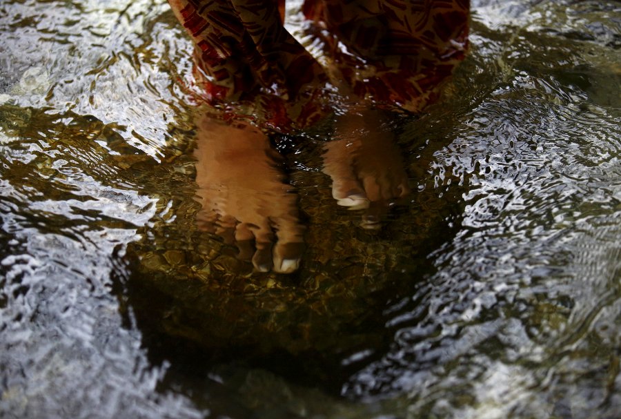Los pies descalzos de un devoto hindú se ven bajo el agua mientras ofrece oraciones en el río Bagmati, durante la peregrinación "Bol Bom" en Katmandú.