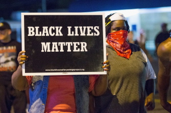 "Las vidas de los negros importan", dice la pancarta de una manifestante anoche en la calle West Florrisant Street de Ferguson, Misuri