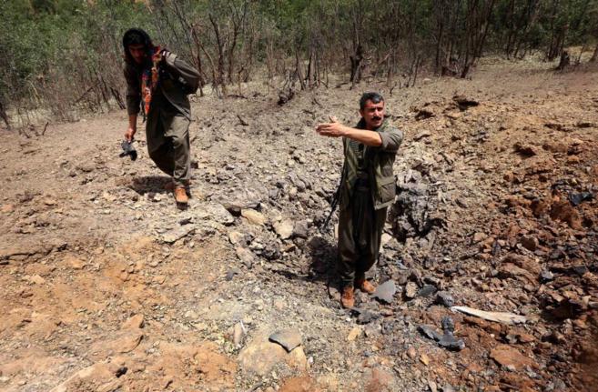 Guerrilleros kurdos del PKK inspeccionan un cráter causado por un ataque aéreo turco