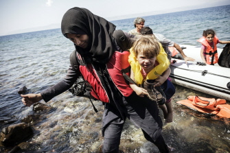 Una mujer siria con su hijo llega a la isla griega de Lesbos, después de cruzar el mar Egeo en un bote inflable desde Turquía