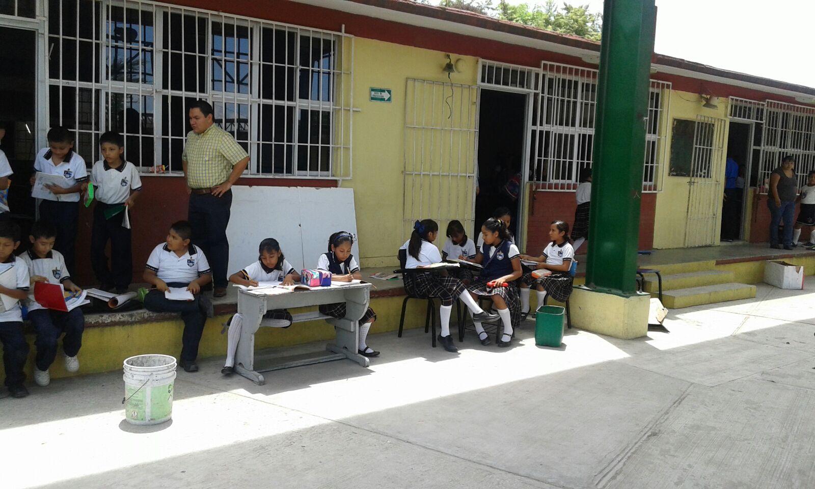 Niños toman clases afuera del salón.
