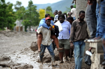 Un grupo de haitianos caminan en la Ruta Nacional 1, entre el lodo de un alud causado por las lluvias causadas por Erika en Montrouis