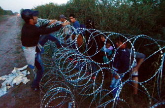 Emigrantes de varios paíes saltan sobre una valla de hierro en la villa de Röszke, en la frontera serbo-húngara 