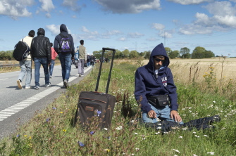 Un emigrante musulmán reza junto a una carretera mientras un grupo de sirios caminan hacia el norte de Dinamarca