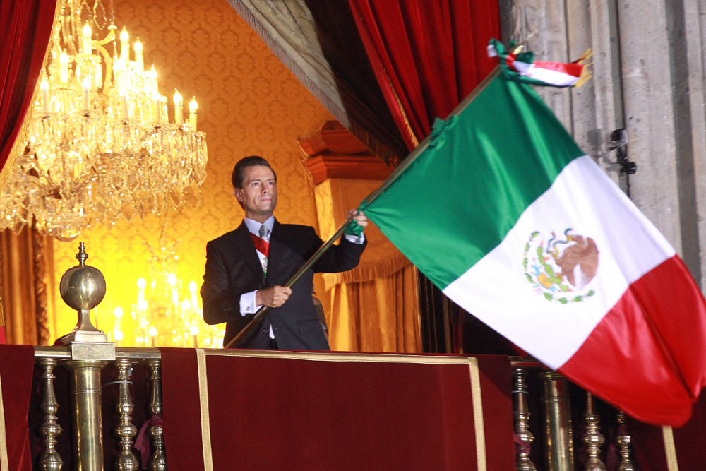 Peña ondea la Bandera Nacional desde el balcón de Palacio Nacional.