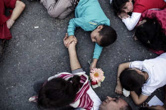 Migrantes sirios protestan en el piso contra el bloqueo de la policía turca a la compra de boletos para ir a Grecia en la terminal Esenler de Estambul