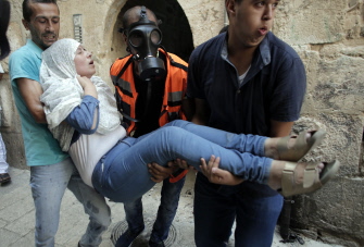 Paramédicos palestinos trasladan a una mujer después de que fuerzas israelíes emplearan gas lacrimógeno, en choques en Jerusalén