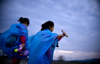 Niñas migrantes juegan con juguetes mientras emigrantes y refugiados hacen cola para ser registrados en un campo en Gevgelija, Macedonia 