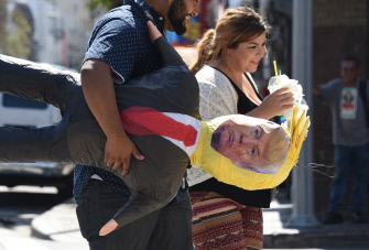 Una pareja latina camina con una piñata de Donald Trump en el centro de Los Ángeles