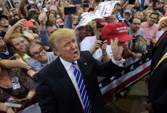 Trump muestra una gorra que ha firmado a un seguidor en un mitin en la Expo Hall de la Richmond International Raceway, en Richmond, Virginia