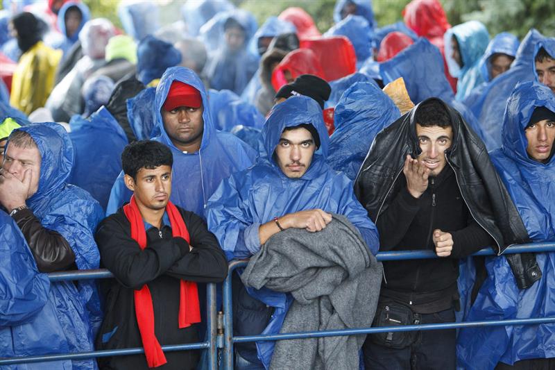 Varios refugiados se protegen de la lluvia mientras esperan en el puesto fronterizo de Trnovec, Croacia