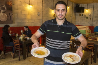 Kobi Tzafrir, el propietario del restaurante Hummus Bar, en la ciudad israelí de Kfar Vitkin, muestra platos de Hummus
