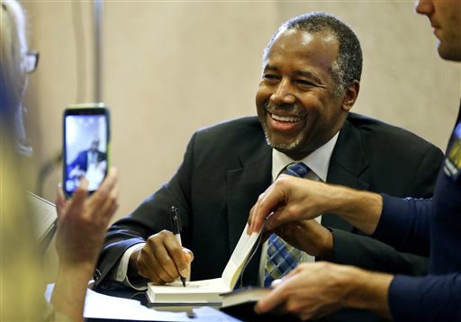 Ben Carson firma una copia de su libro "Una Unión más perfecta" mientras una simpatizante le fotografía en Barnes & Nobel in Topeka, Kansas