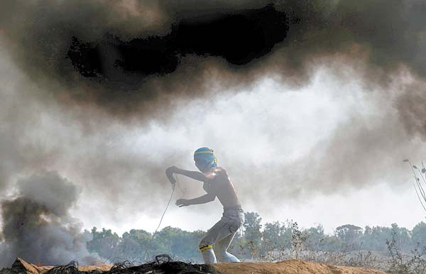Joven de la Franja de Gaza lanza piedras a tropas israelíes cerca de la frontera.