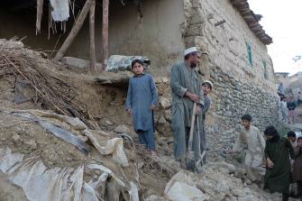 Varias personas se reúnen junto a las ruinas de un edificio derrumbado por el sismo en Bajaur, Pakistán