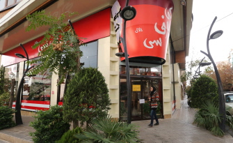 Una mujer pasa junto al "KFC Halal", imitador del gigante de comida rápida estadunidense del Pollo Frito, en Teherán, tras ser clausurado 
